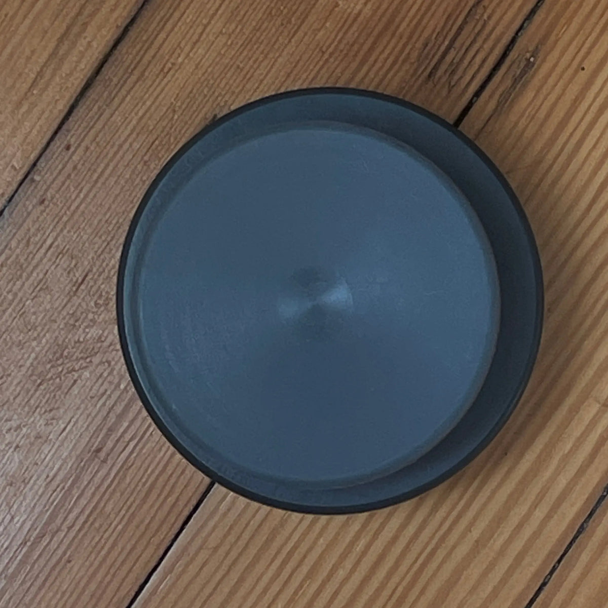 Mini Xeno stacked on top of a traditional Xenopuck, photographed from directly above on a rustic wooden plank floor.